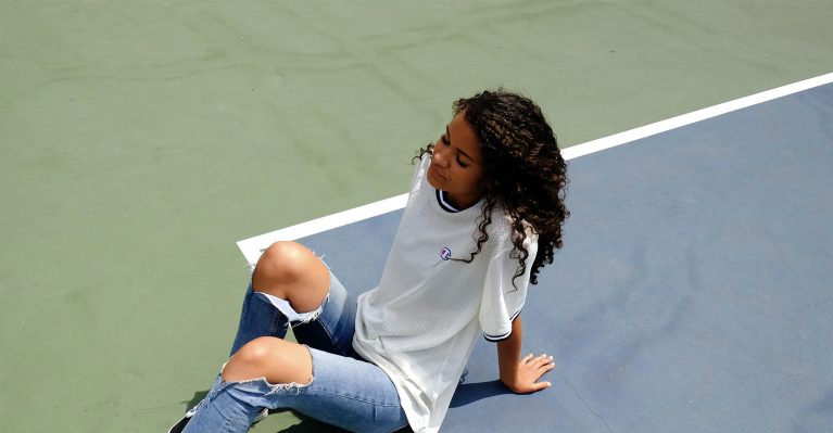 young ambiguous woman sitting on a tennis court